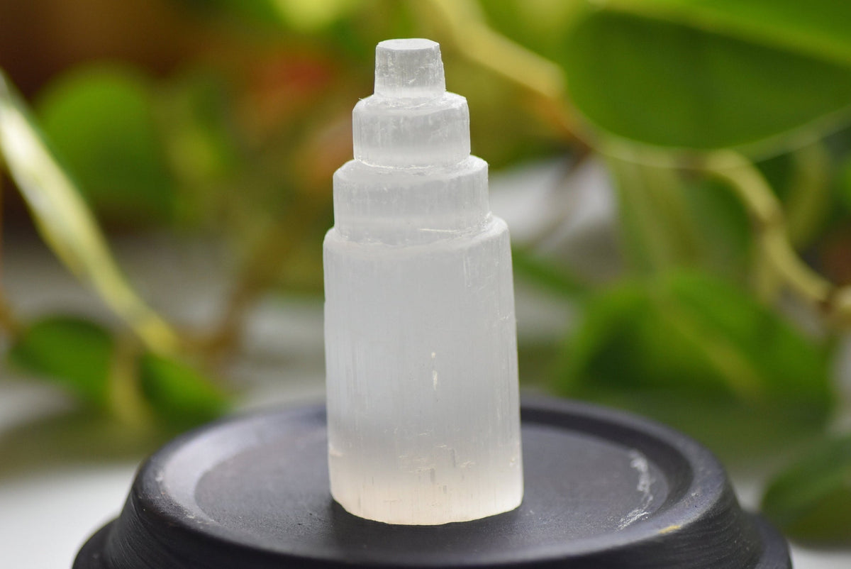 Frosted glass stone tower on a black stand with green foliage in the background