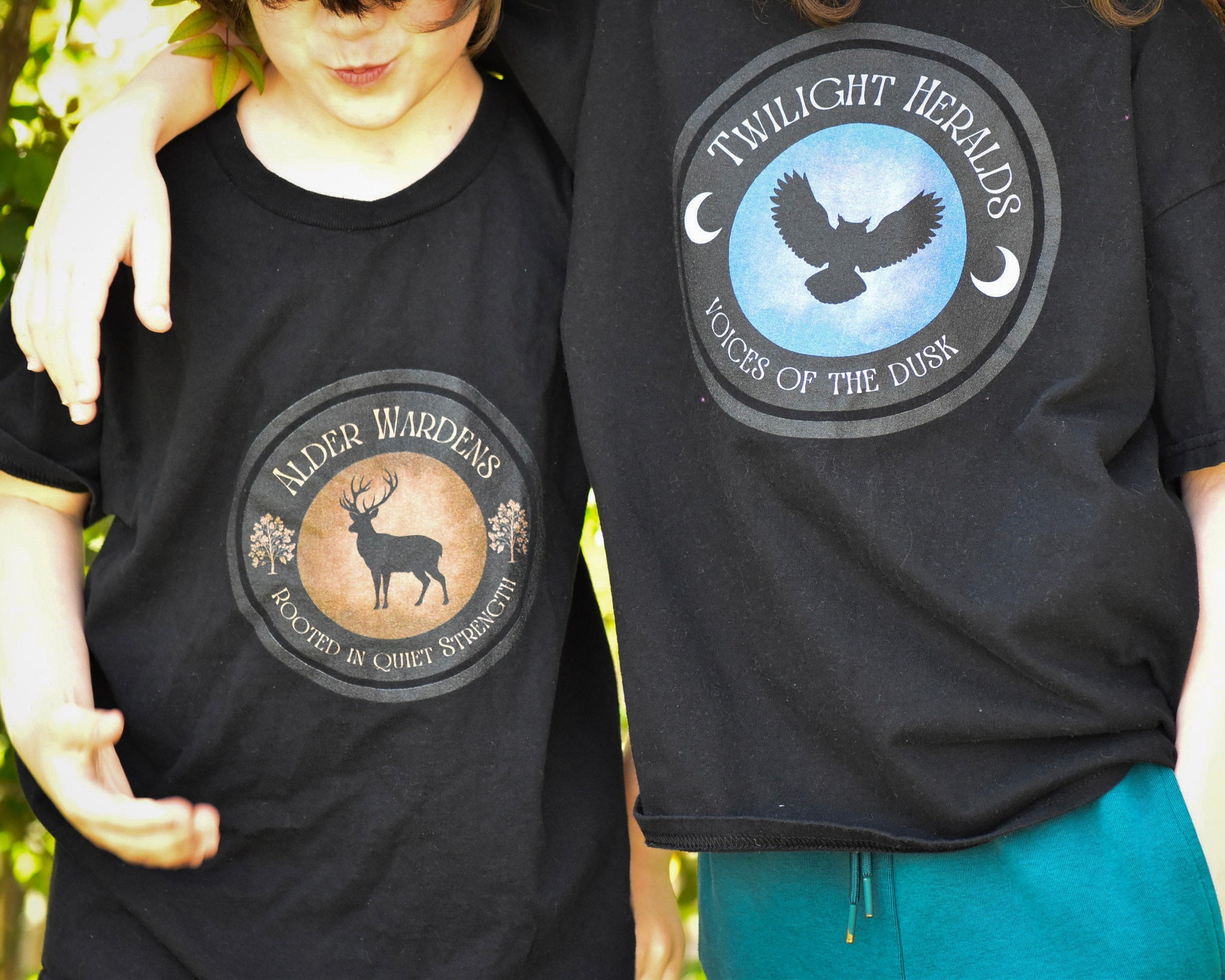 Two people wearing black t-shirts with circular designs featuring animals and text.