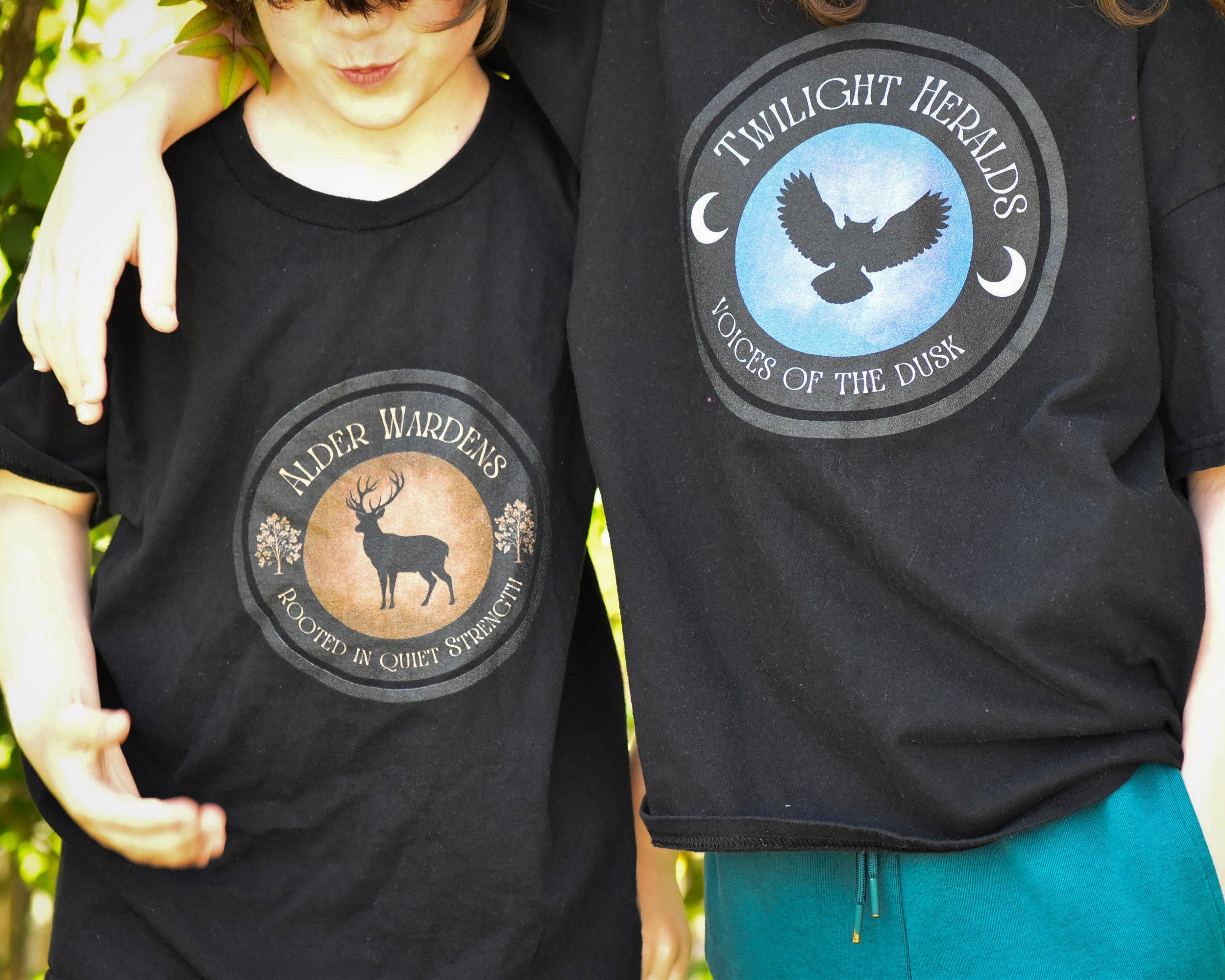 Two people wearing black t-shirts with circular designs featuring animals and text.