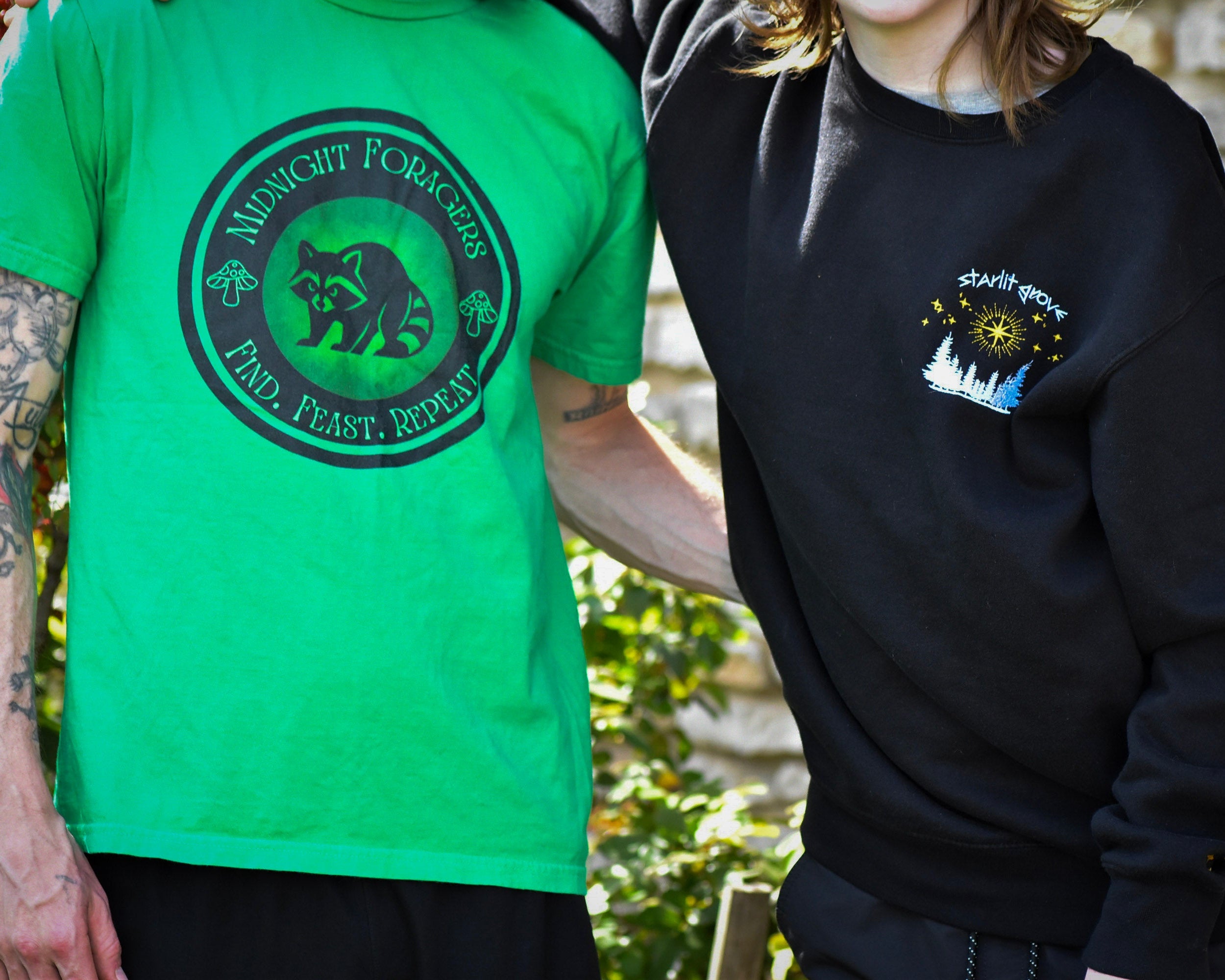 Two people wearing green and black shirts with logos, standing outdoors.